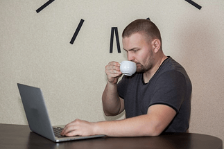 Man working on his laptop and drinking coffee